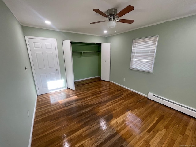 unfurnished bedroom featuring a baseboard heating unit, baseboards, ornamental molding, and wood finished floors