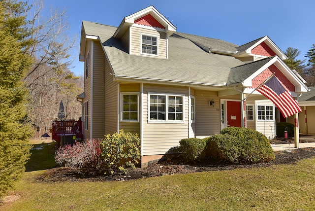 view of front of house with a shingled roof and a front lawn