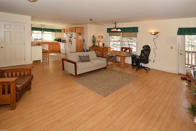 living room featuring light wood finished floors, plenty of natural light, and baseboards