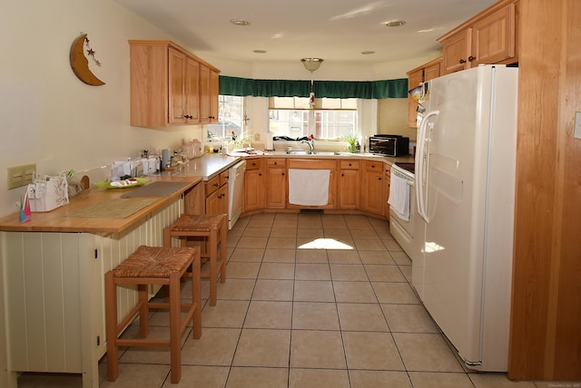 kitchen with a toaster, light tile patterned floors, light countertops, a sink, and white appliances