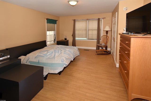 bedroom featuring light wood-style floors, visible vents, and baseboards