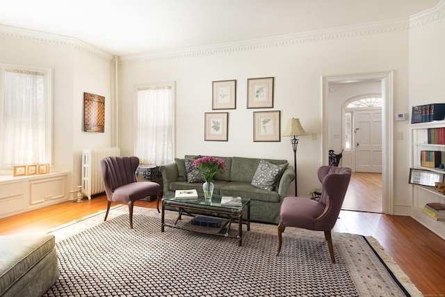 living room with ornamental molding, light wood-type flooring, and radiator