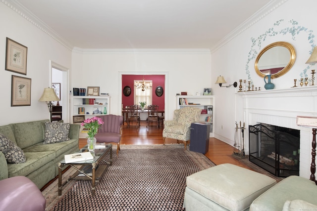 living room with a notable chandelier, a fireplace, wood finished floors, baseboards, and ornamental molding