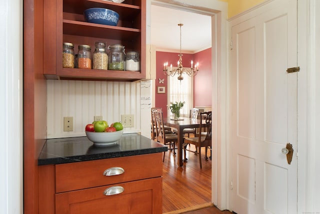 bar featuring a chandelier, wood finished floors, and crown molding