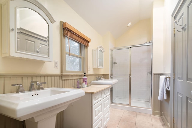 bathroom featuring lofted ceiling, tile patterned flooring, a sink, wainscoting, and a shower stall