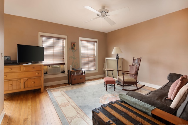 living area with light wood-style flooring, baseboards, ceiling fan, and cooling unit