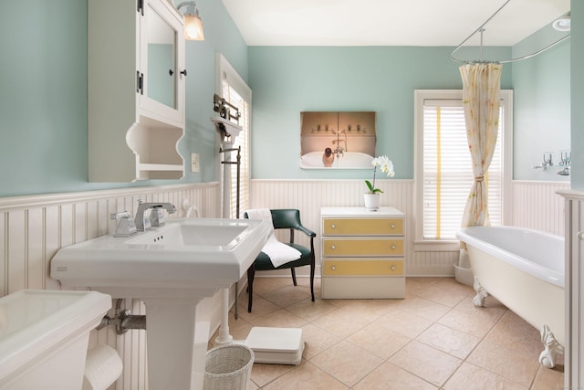 full bath featuring a wainscoted wall, a freestanding bath, and tile patterned flooring