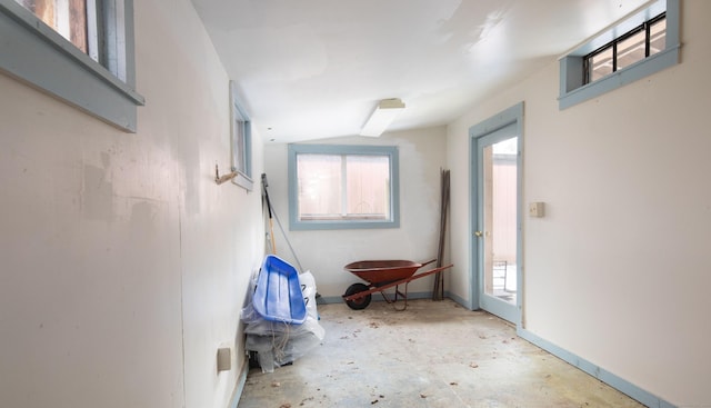 corridor with unfinished concrete flooring and baseboards