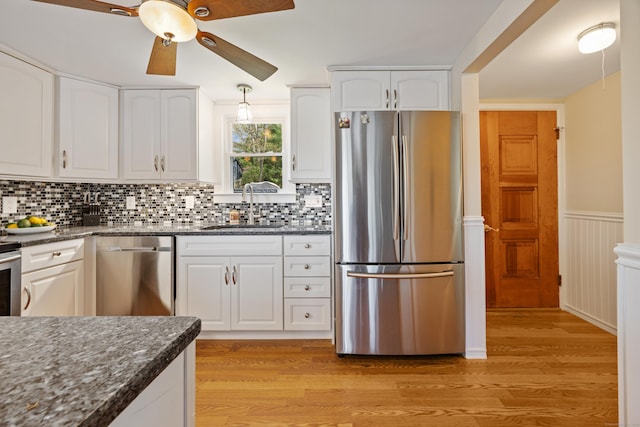 kitchen with ceiling fan, a sink, light wood-style floors, stainless steel appliances, and white cabinetry