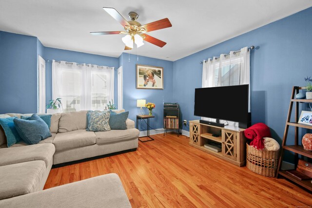 living room featuring baseboards, ceiling fan, wood finished floors, and a healthy amount of sunlight