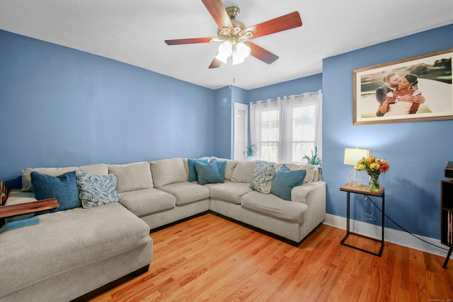 living room with light wood-type flooring, ceiling fan, and baseboards