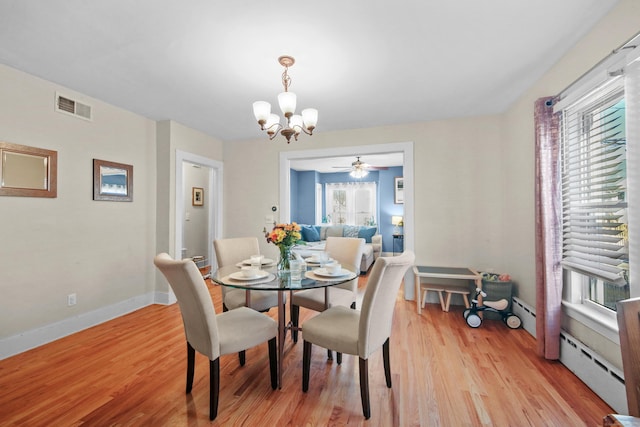 dining space featuring light wood-style flooring, baseboard heating, visible vents, and a notable chandelier