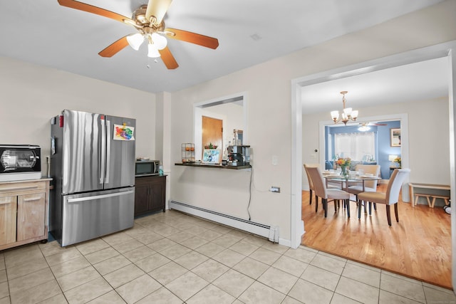 kitchen featuring stainless steel appliances, a baseboard radiator, ceiling fan with notable chandelier, and light tile patterned floors