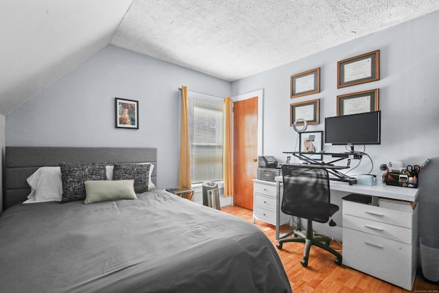 bedroom with light wood-style floors, vaulted ceiling, and a textured ceiling