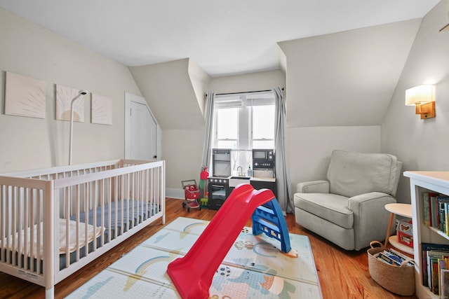 bedroom featuring lofted ceiling, wood finished floors, and baseboards