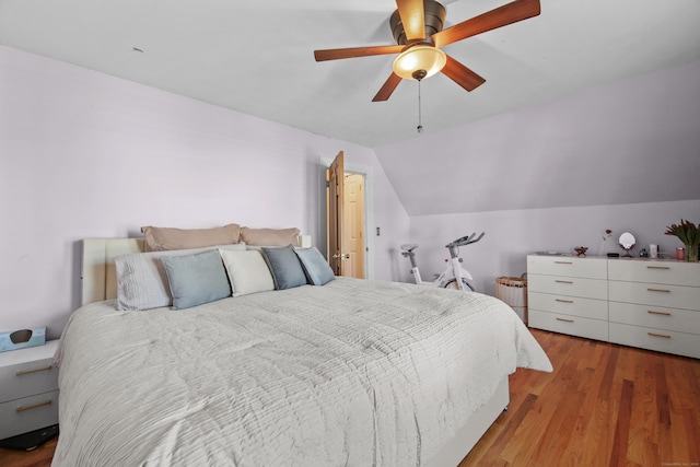 bedroom with a ceiling fan, lofted ceiling, and wood finished floors