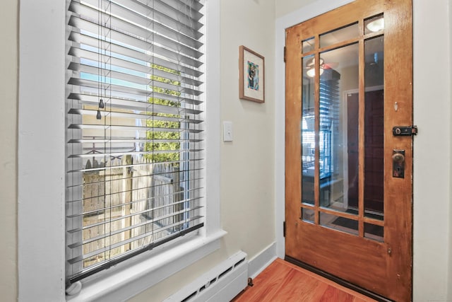 foyer entrance with a baseboard radiator, baseboards, and wood finished floors