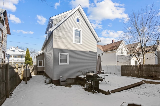 snow covered house with a fenced backyard