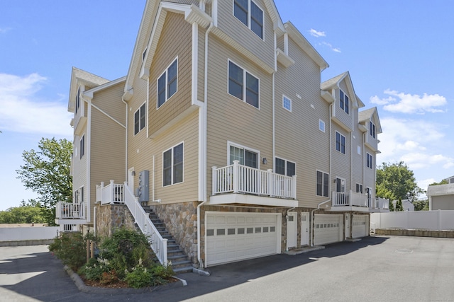 view of building exterior featuring stairs, aphalt driveway, and an attached garage