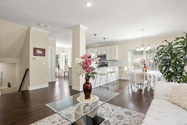 living area with ornamental molding, dark wood-style flooring, a notable chandelier, and baseboards