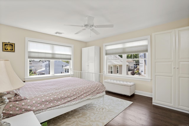 bedroom featuring dark wood-style floors, a ceiling fan, visible vents, and baseboards