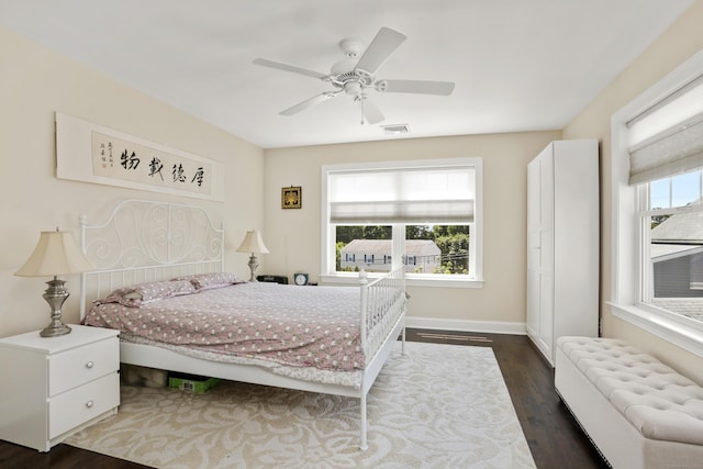 bedroom featuring dark wood-style floors, radiator heating unit, multiple windows, and visible vents