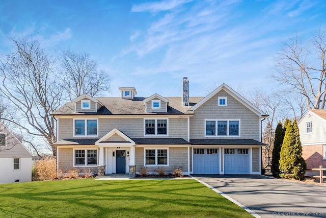 view of front of house featuring an attached garage, a chimney, a front lawn, and aphalt driveway