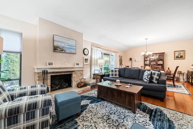 living area with lofted ceiling, a fireplace, a notable chandelier, and wood finished floors