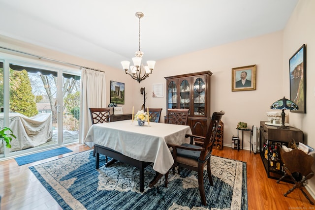 dining area with an inviting chandelier, baseboards, and wood finished floors