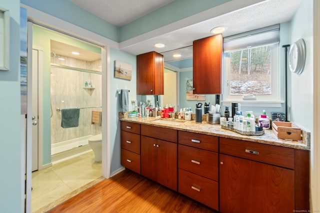 full bathroom with baseboards, toilet, wood finished floors, vanity, and a shower stall