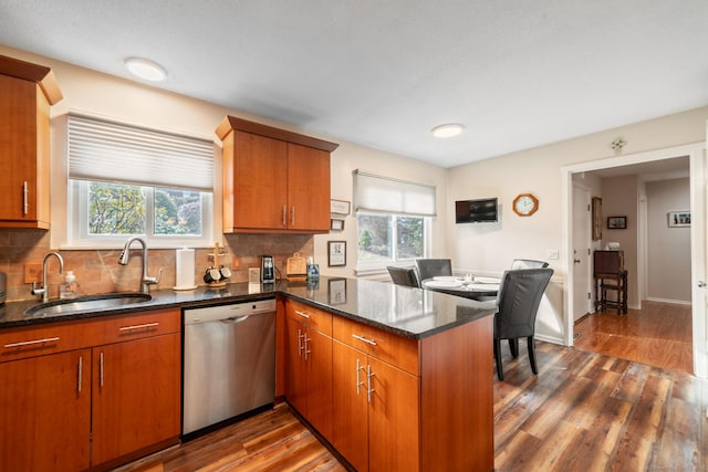 kitchen with a healthy amount of sunlight, dishwasher, a peninsula, and a sink