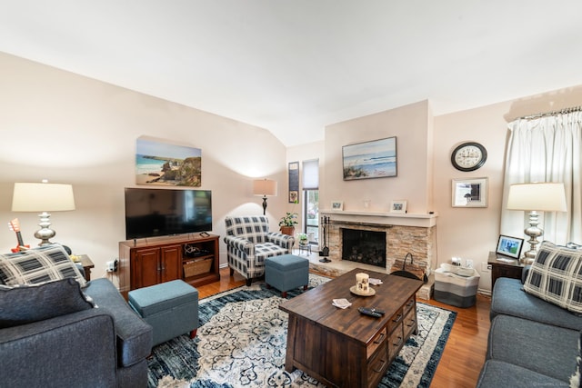 living area featuring vaulted ceiling, a fireplace, wood finished floors, and baseboards