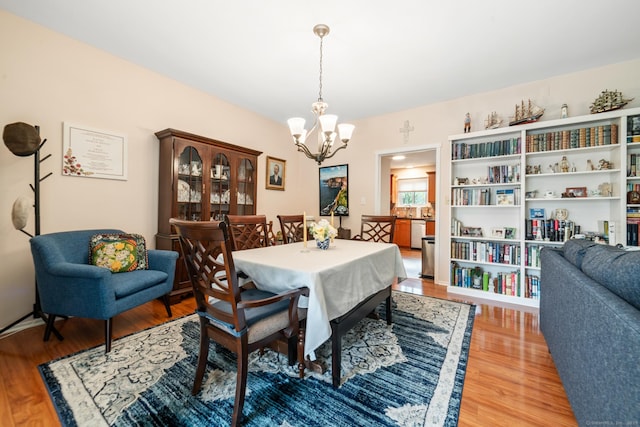 dining space with light wood finished floors and an inviting chandelier