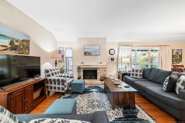 living room featuring light wood-style flooring and a stone fireplace