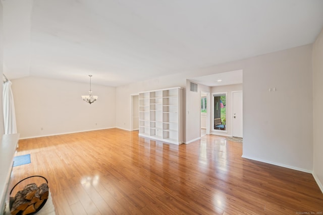 unfurnished living room featuring light wood-type flooring, baseboards, visible vents, and a chandelier