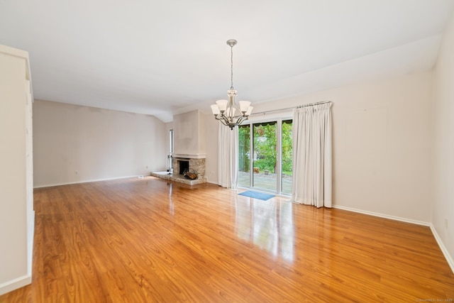 unfurnished living room with a chandelier, light wood-style floors, a fireplace, and baseboards