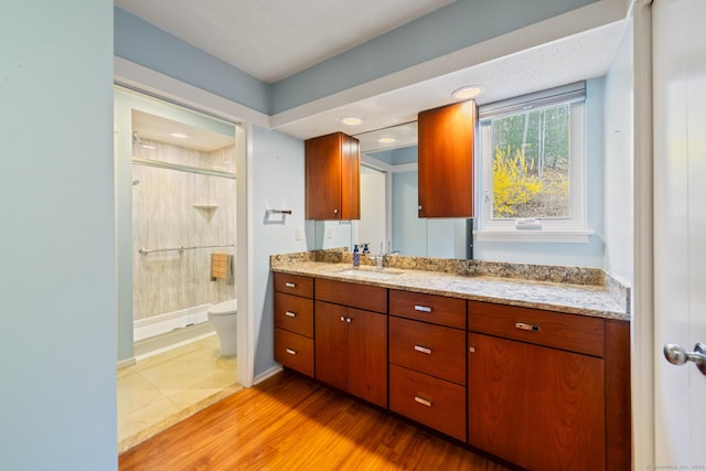 full bathroom featuring wood finished floors, vanity, a shower stall, and toilet