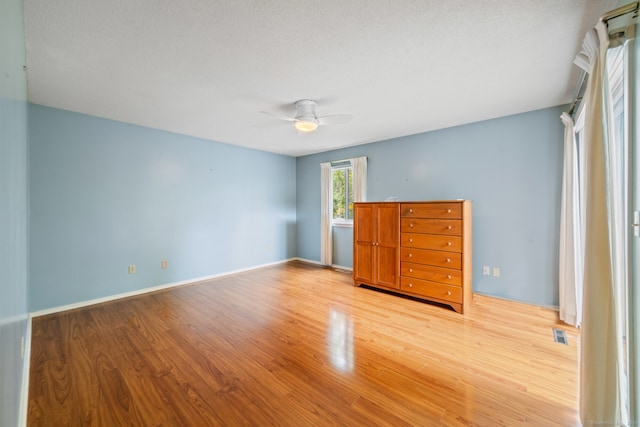 spare room with baseboards, a ceiling fan, wood finished floors, and visible vents