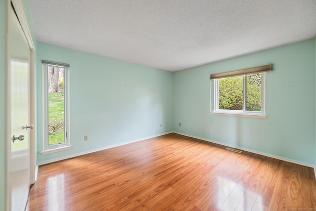 unfurnished room featuring wood finished floors, a textured ceiling, and a healthy amount of sunlight