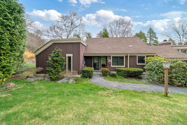 single story home featuring a chimney, a front lawn, roof with shingles, and board and batten siding
