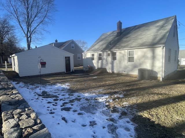 snow covered rear of property with central air condition unit and a chimney