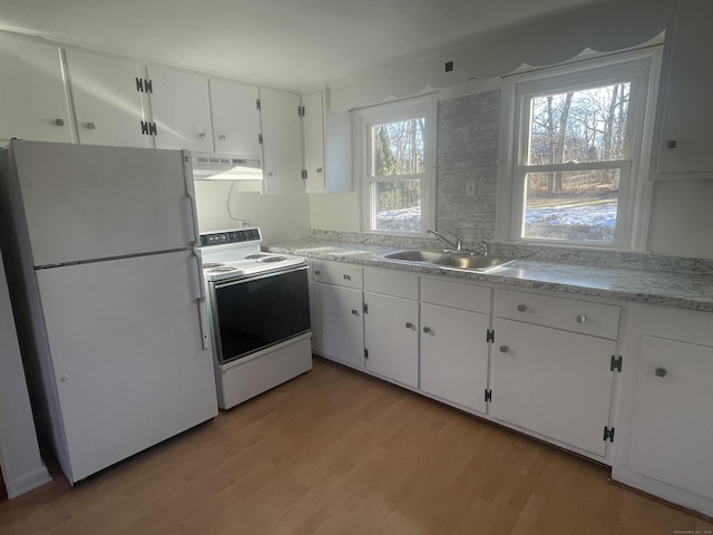 kitchen with white appliances, white cabinets, light wood-type flooring, under cabinet range hood, and a sink