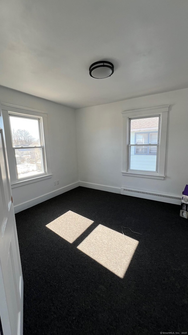 empty room with baseboards, carpet flooring, and baseboard heating