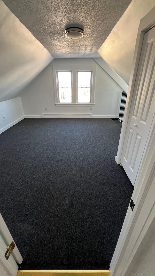 bonus room featuring baseboards, lofted ceiling, dark colored carpet, a textured ceiling, and a baseboard heating unit