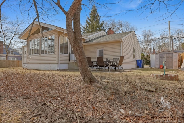 view of property exterior with an outbuilding, a patio, a shingled roof, a shed, and a chimney