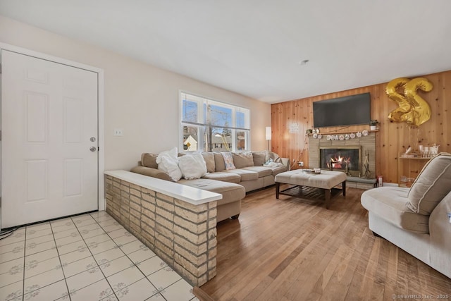 living area with wood walls, light wood-type flooring, and a glass covered fireplace