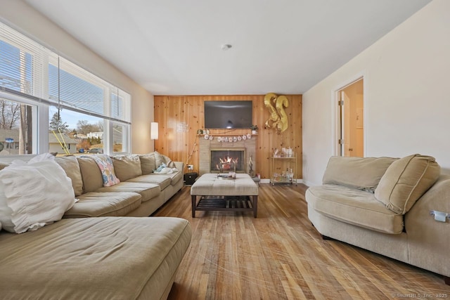 living room with wooden walls, baseboards, a fireplace, and wood finished floors