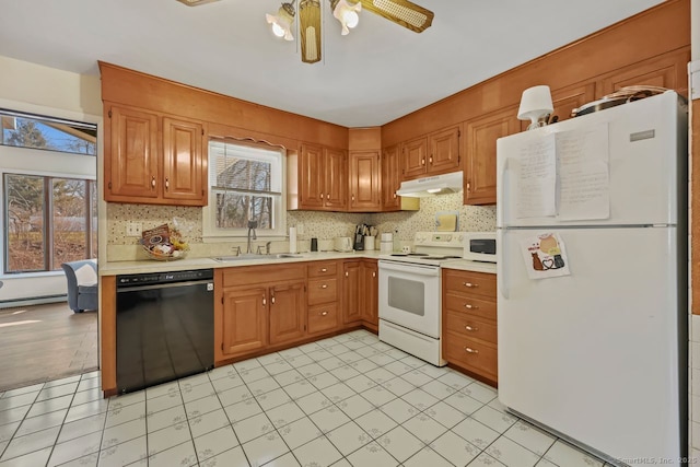 kitchen with white appliances, under cabinet range hood, light countertops, and a sink