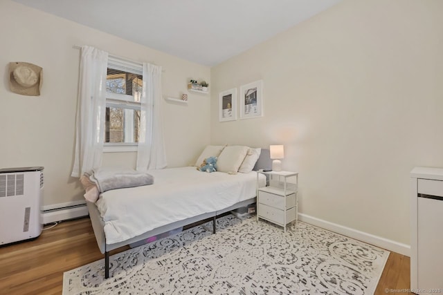 bedroom featuring baseboards, a baseboard radiator, and light wood-style floors