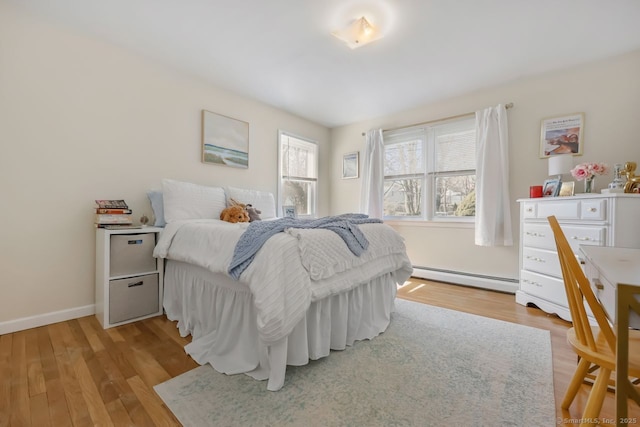 bedroom with a baseboard radiator, baseboards, and wood finished floors